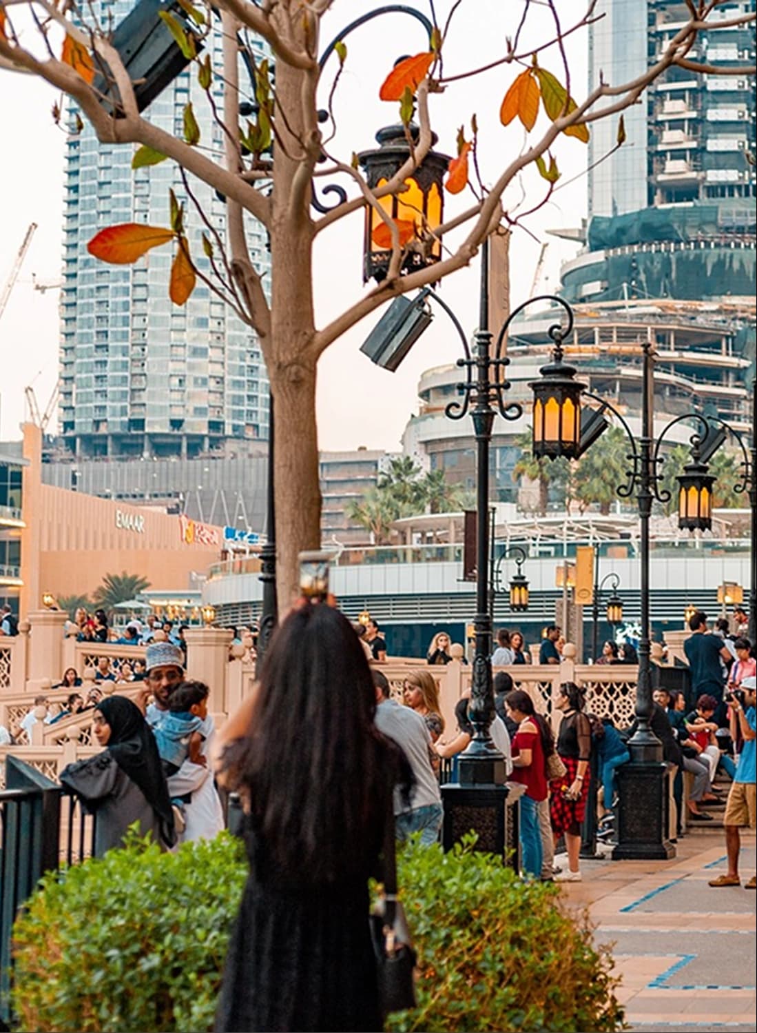 People strolling along tree-lined path with city buildings