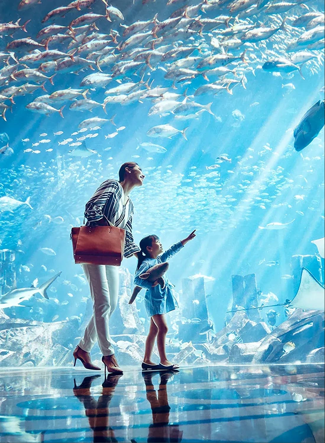 Mother and child at an aquarium looking at marine life