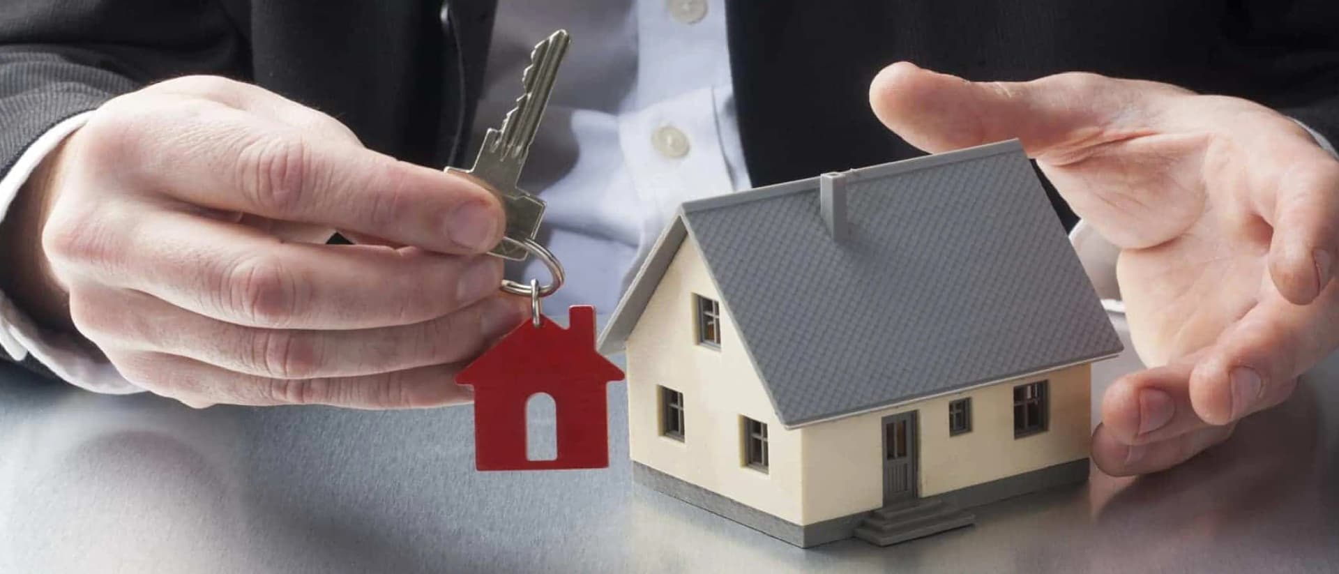 Hands holding keys with a house keychain and model