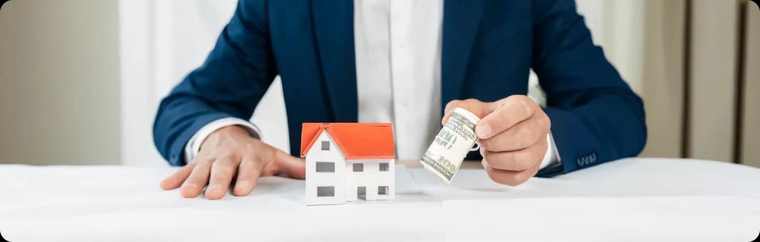 Person in a suit with money and a small house model