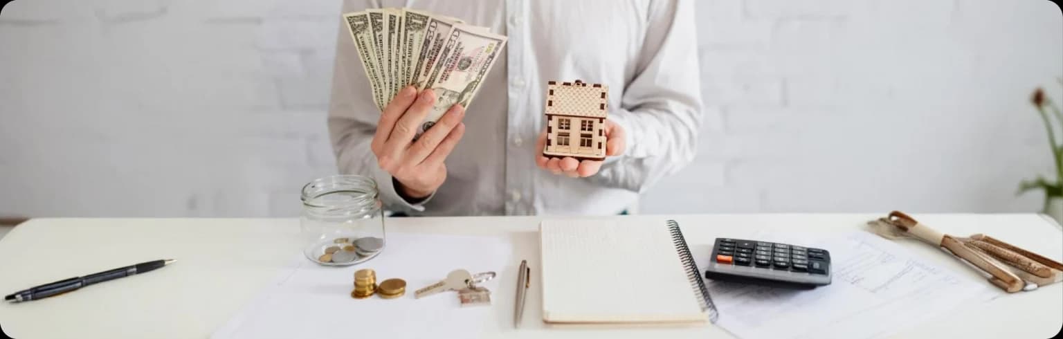 Hands holding money and a small house model