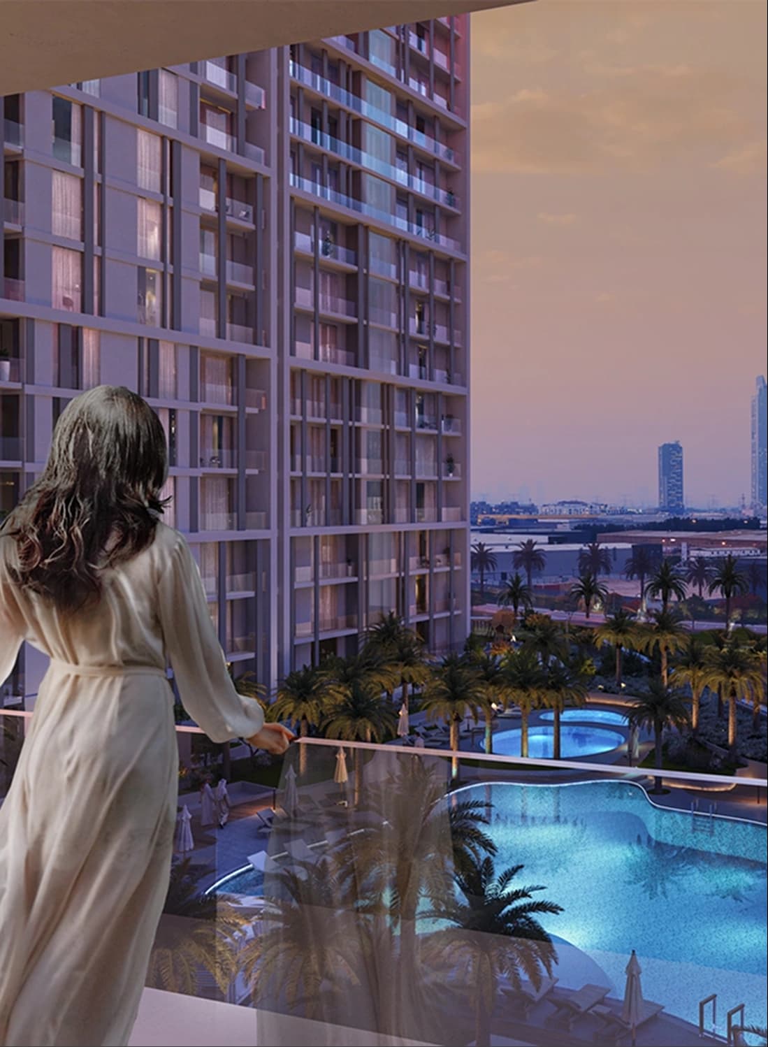 Woman on a balcony overlooking a pool and palm trees at sunset