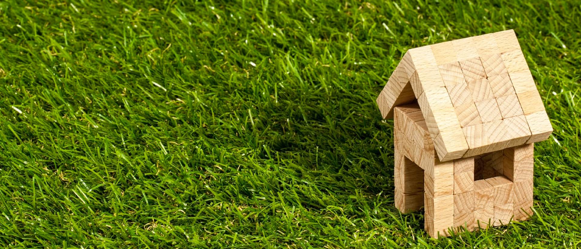 Small wooden block house on green artificial grass