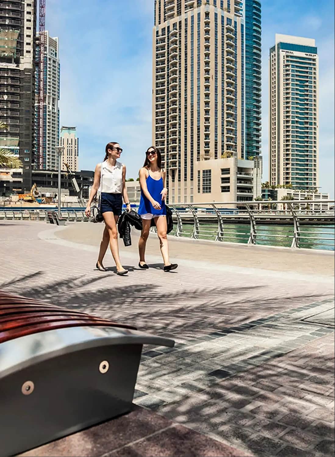 Two women walking along a modern city waterfront