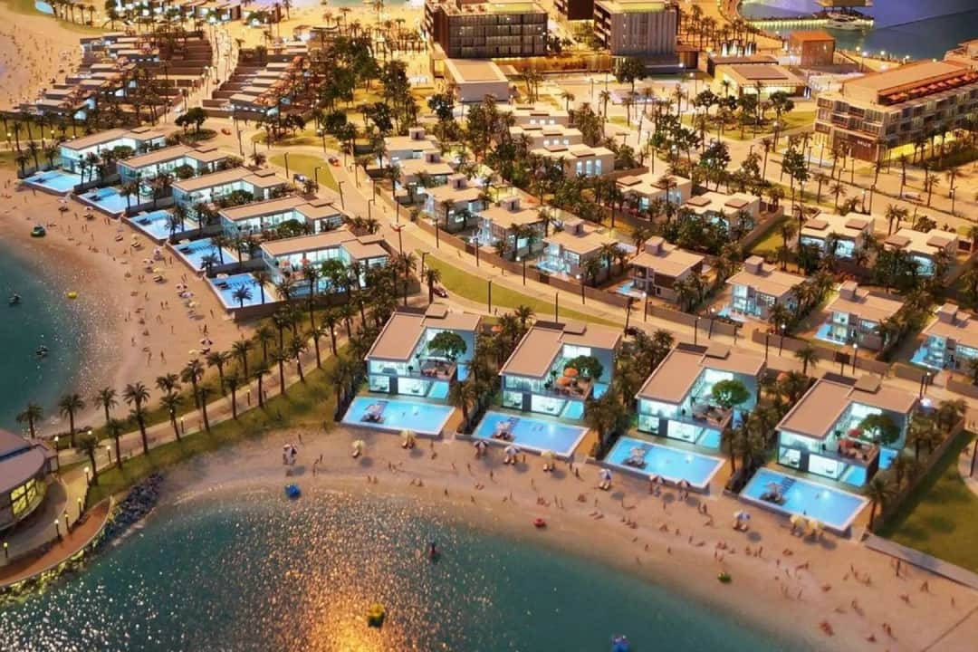 Nighttime model of beachfront villas with illuminated pools