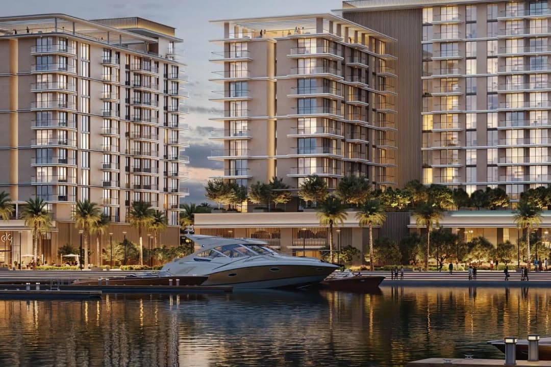 Residential towers with a marina and palm-lined promenade at dusk