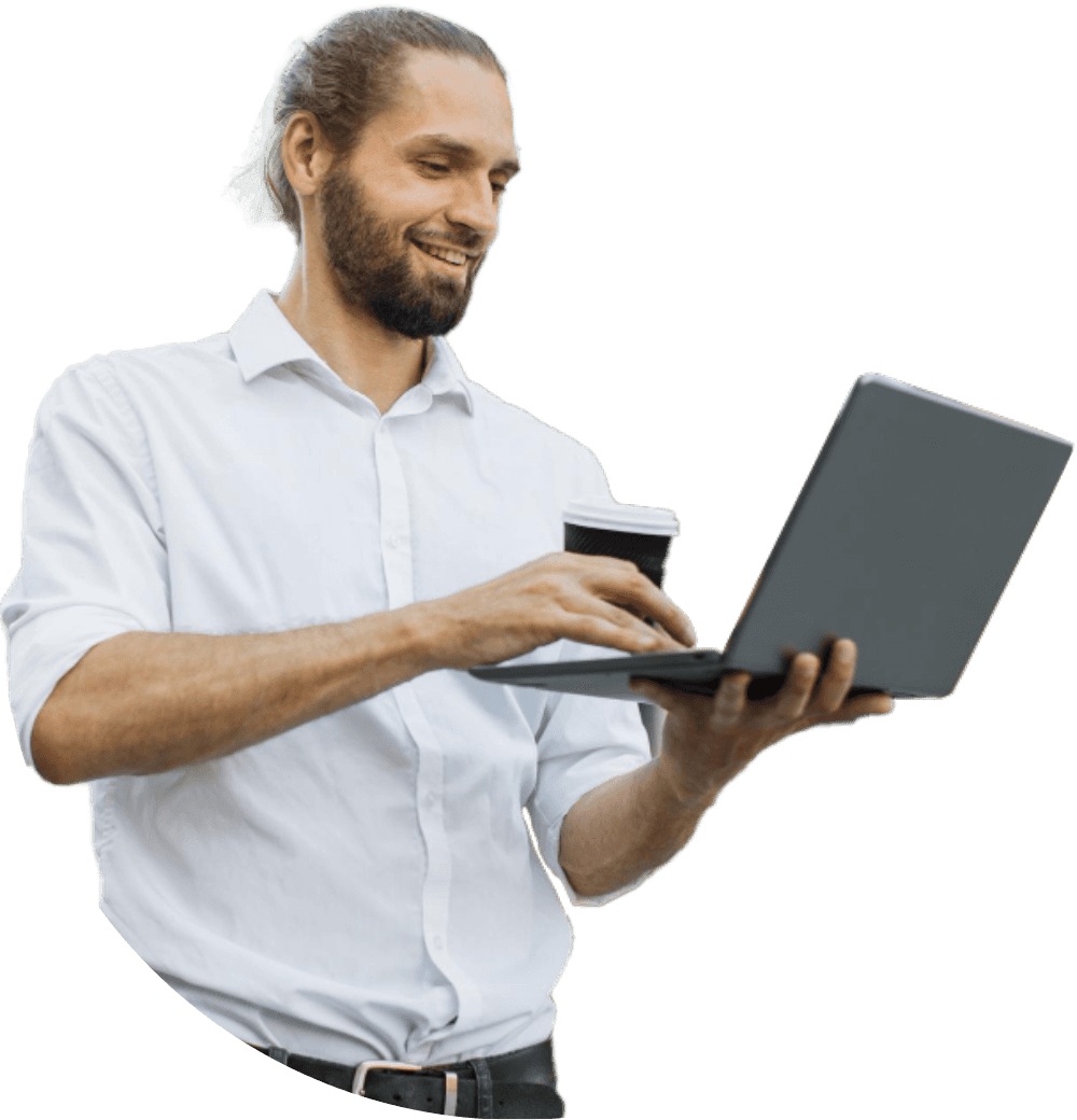 Man smiling while working on a laptop with a coffee cup