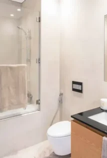 Clean and bright bathroom with a toilet, sink with faucet, and a shower