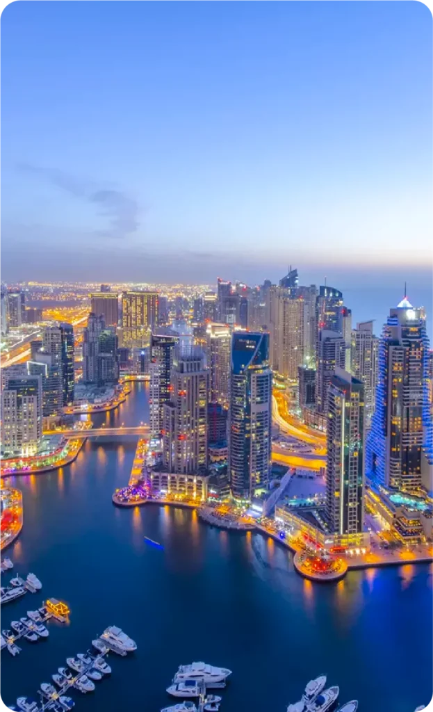 Aerial view of Dubai Marina with illuminated skyscrapers and waterways at dusk.