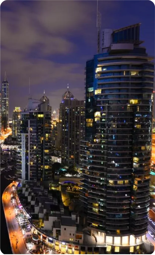 Night view of Dubai Marina with illuminated skyscrapers and bustling waterfront.