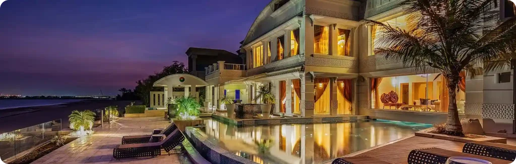 Luxurious waterfront villa with a private pool, palm trees, and elegant lighting, set against a serene evening backdrop.